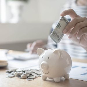 a person adding money to a piggy bank